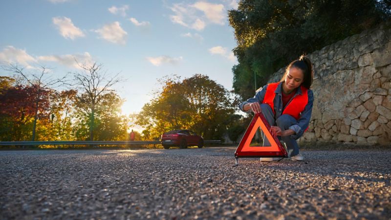 Una ragazza posiziona il triangolo sul ciglio della strada