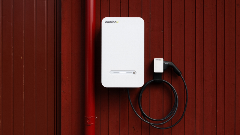 Detaljbild av en vit laddbox från Ambibox. Uppsatt på en faluröd vägg