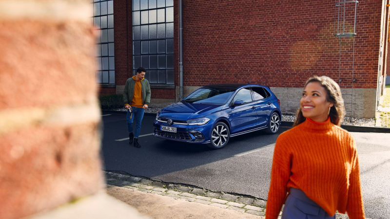 Frau und Mann entfernen sich von einem geparkten VW Polo – Volkswagen Zubehör Katalog online entdecken