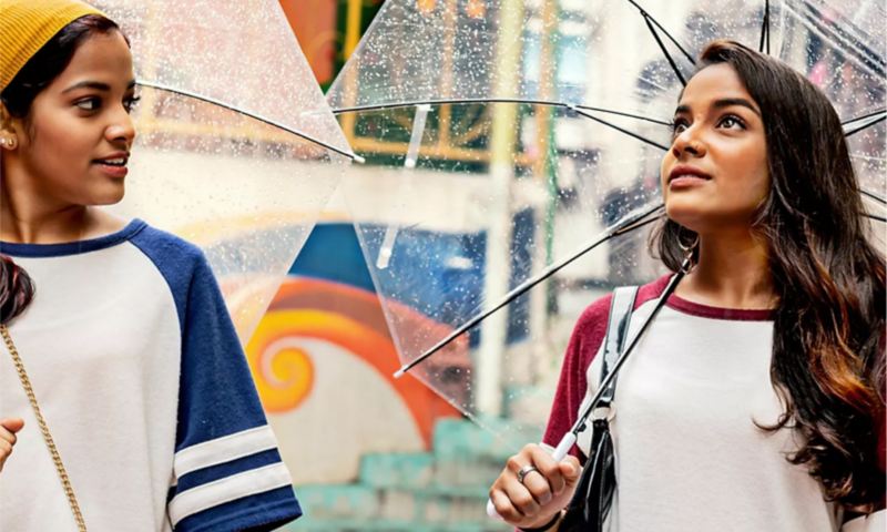 Two women walking with umbrellas.