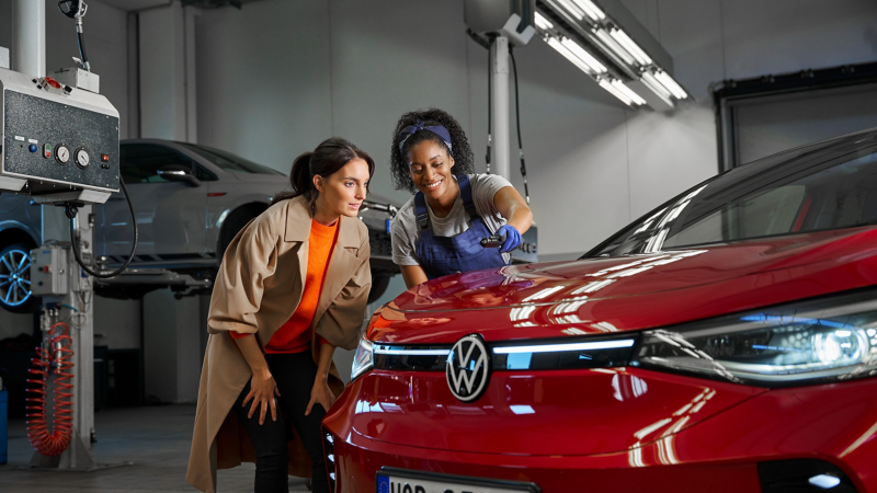 Un empleado del servicio técnico de VW y un cliente observan la pintura de un VW ID.5 GTX