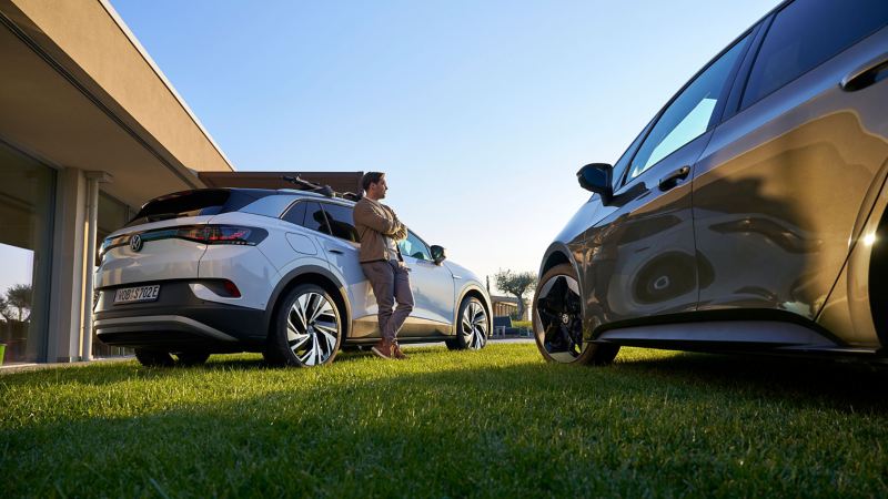 Man leans against a VW ID.4, another VW ID. model in foreground