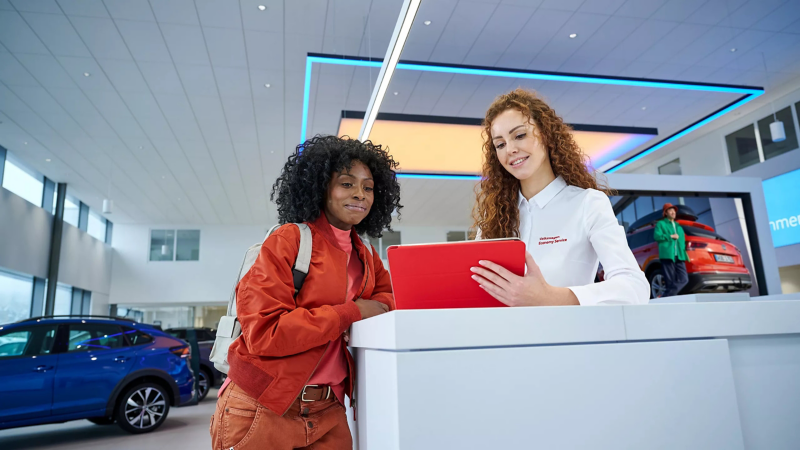 Volkswagen servicemedewerker laat iets zien aan klant op tablet, ze staan binnen bij de receptie