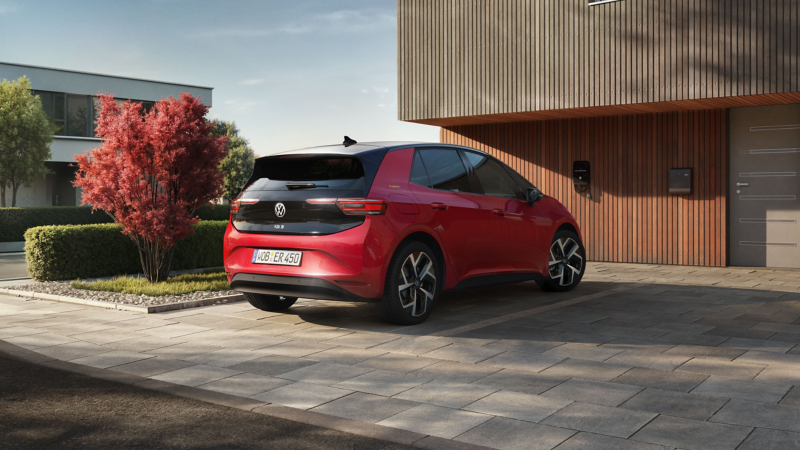 Heckansicht roter VW ID.3, der vor modernem Haus mit Holzfassade parkt