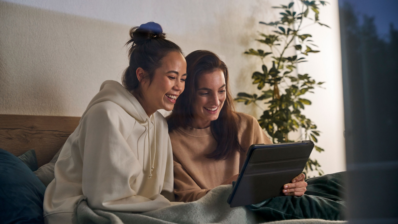 Zwei Frauen schauen lächelnd auf ein Tablet