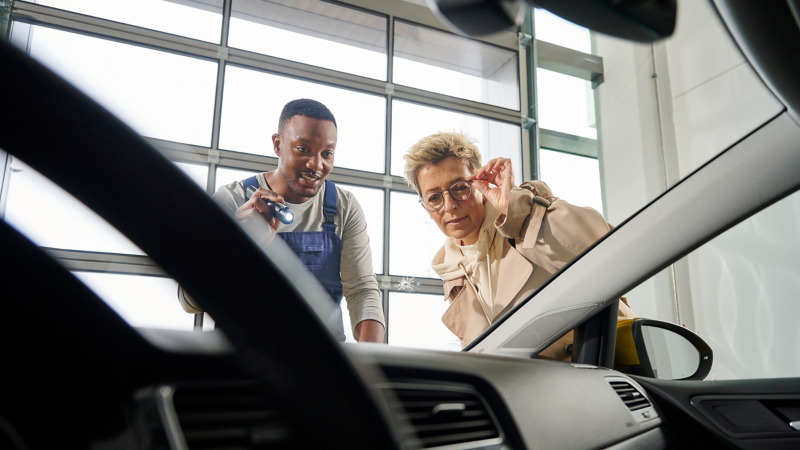 VW service employee and customer look at the stone chip on a windscreen