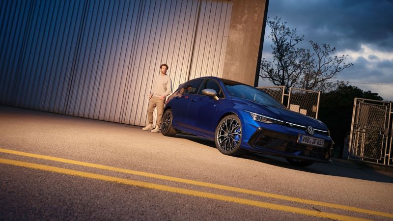 Man next to VW Golf R in front of a factory building