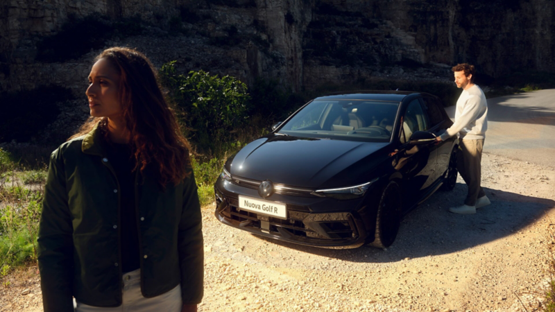 Photo showing a black VW car with two people next to it. 