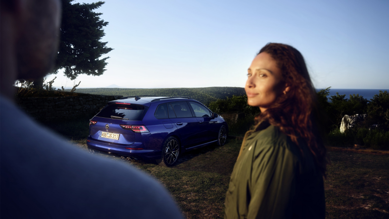 VW Golf R Variant, w tle morze, na pierwszym planie kobieta.