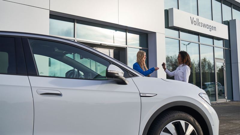 Eine VW Servicemitarbeiterin übergibt die Autoschlüssel eines ID. Autos an eine Kundin