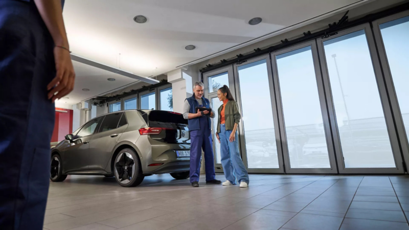 Volkswagen servicemedewerker en klant naast Volkswagen ID.3 kijkend naar een tablet