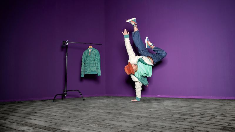 Mann mit Wendejacke aus der ID. Buzz Kollektion macht einarmigen Handstand – VW Fanartikel