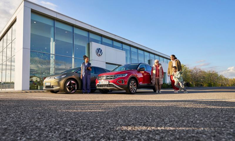 VW dealership, customers at the front and VW service employee next to VW ID.3 and VW T-Roc