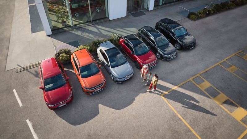 Eine Familie neben sechs Volkswagen Vorgängermodellen auf einem Parkplatz