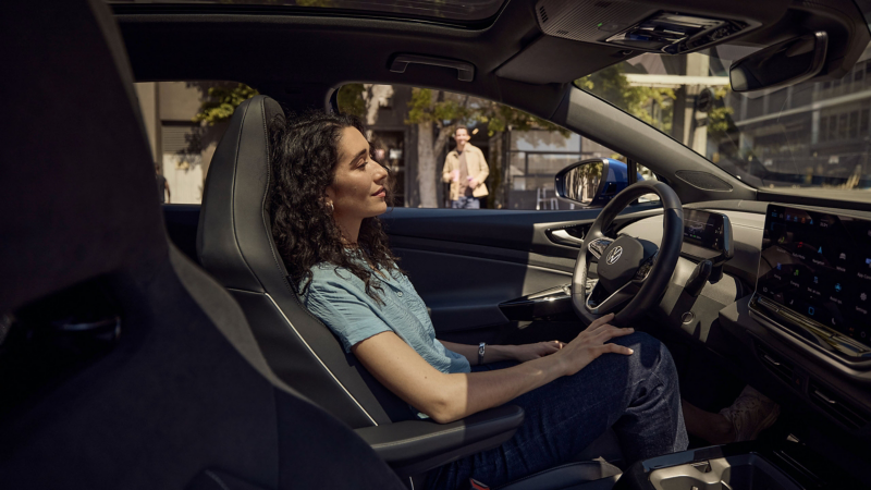 Blick in den Innenraum eines VW Autos, Frau auf Fahrersitz.