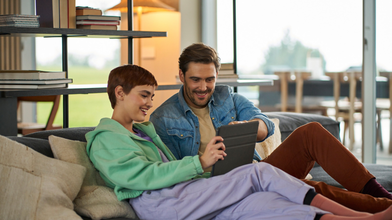 Mann und Frau schauen gemeinsam auf ein Tablet und informieren sich über VW