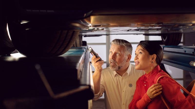 Empleado del servicio técnico de Volkswagen le muestra a una clienta algo sobre su coche eléctrico