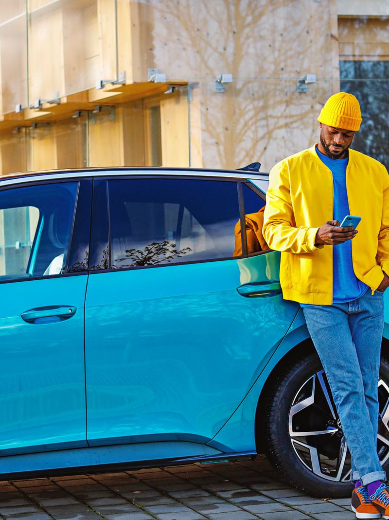 Un uomo con una giacca gialla si appoggia alla sua Volkswagen ID.