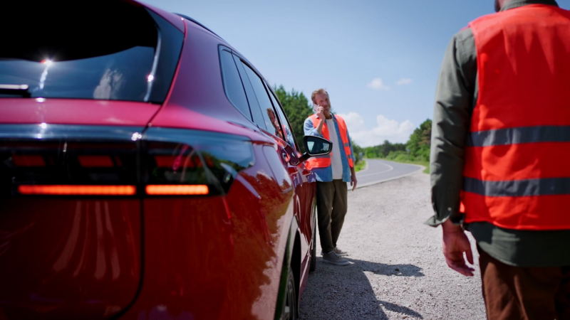 Man met veiligheidshesje aan staat te bellen naast een Volkswagen