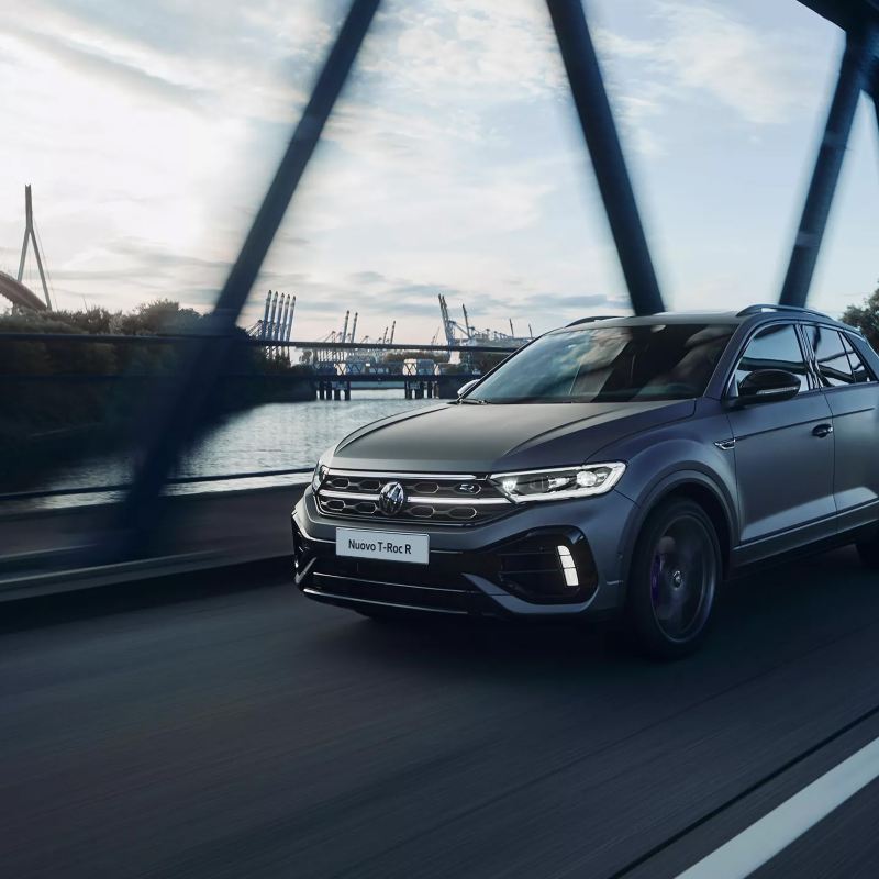 Volkswagen Nuovo T-Roc R sfreccia su strada. Sullo sfondo, le montagne.