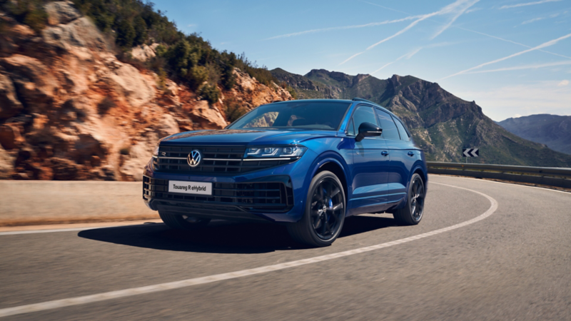 Una Touareg R eHybrid percorre una curva, sullo sfondo montagne