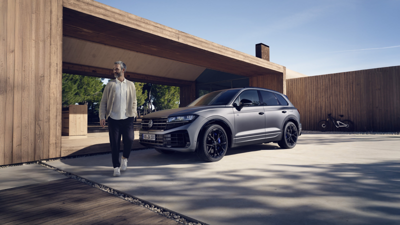 Der Touareg R eHybrid von VWR fährt um eine Kurve, im Hintergrund die Berge