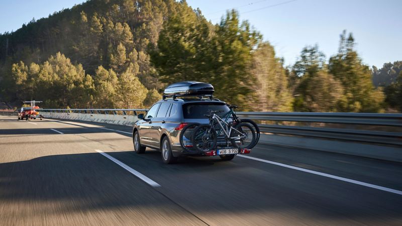 VW Tiguan Allspace mit VW Zubehör Dachbox und Fahrradträger fährt hinter VW ID.5 GTX mit Kajakanhänger