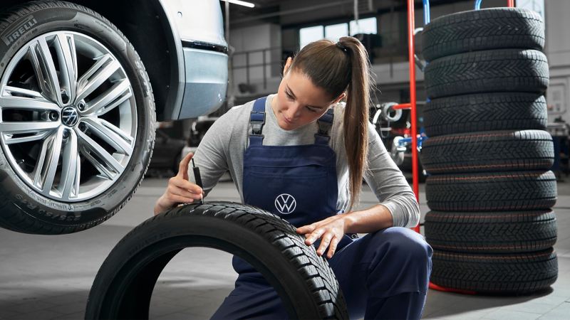 Une collaboratrice d’atelier Volkswagen vérifie le profil d’un pneu Volkswagen