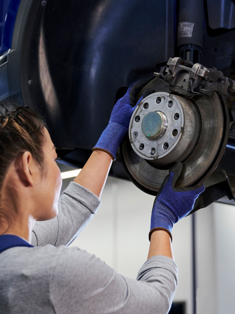 Une employée du service Entretien VW inspecte le disque de frein d’une voiture VW