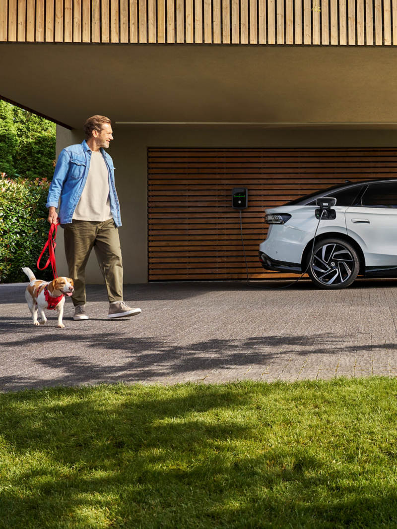 Mężczyzna z psem obok samochodu VW Wallbox