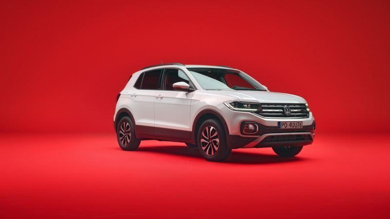 Biały VW T-Cross widziany z przodu i z boku na czerwonym tle.