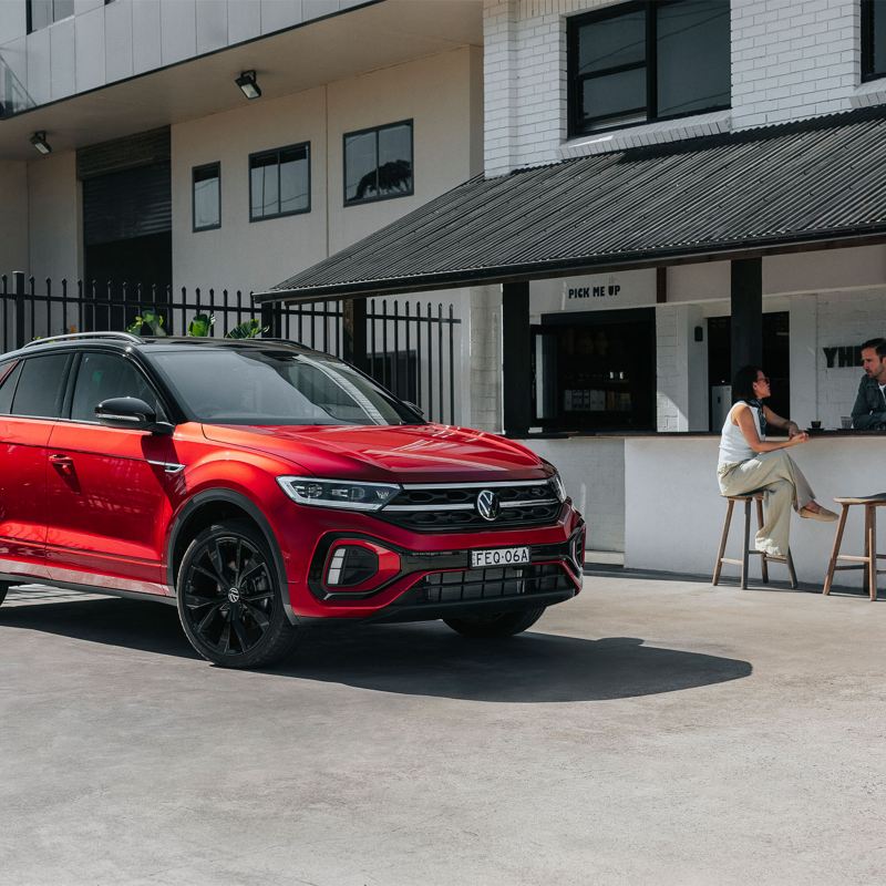 Couple sitting having coffee T-roc in back