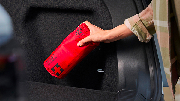 Una persona ripone nel bagagliaio il kit di sicurezza per il soccorso stradale Volkswagen.