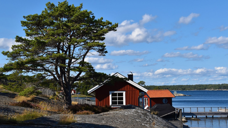 En rös stuga på klipporna vid havet i Sandhamn