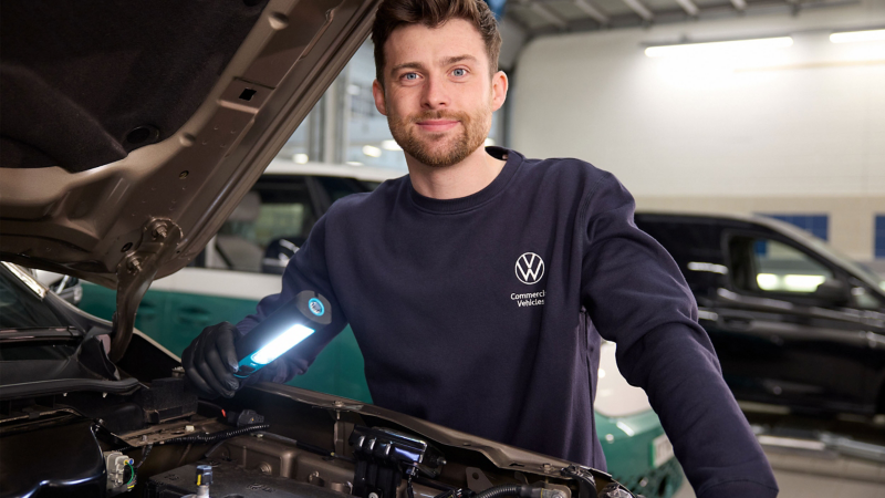 Man wearing red overalls and gloves working on a car