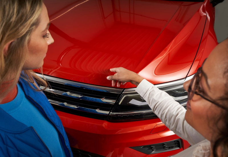 Une technicienne du service entretien et une cliente inspectent la carrosserie d'une Volkswagen