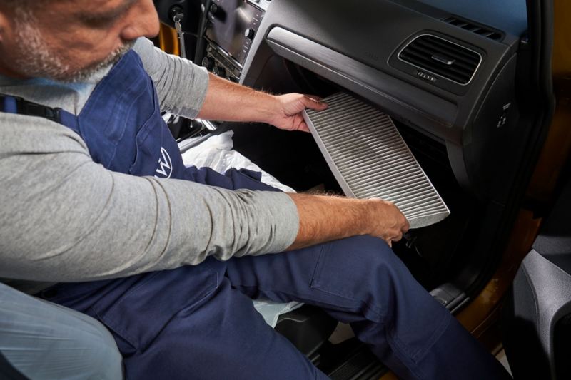 Un employé de Volkswagen effectue l'entretien de la climatisation d'un véhicule Volkswagen
