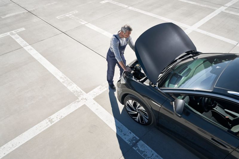 Un techniciennVolkswagen effectue inspecte le moteur d'une Volkswagen sur un parking