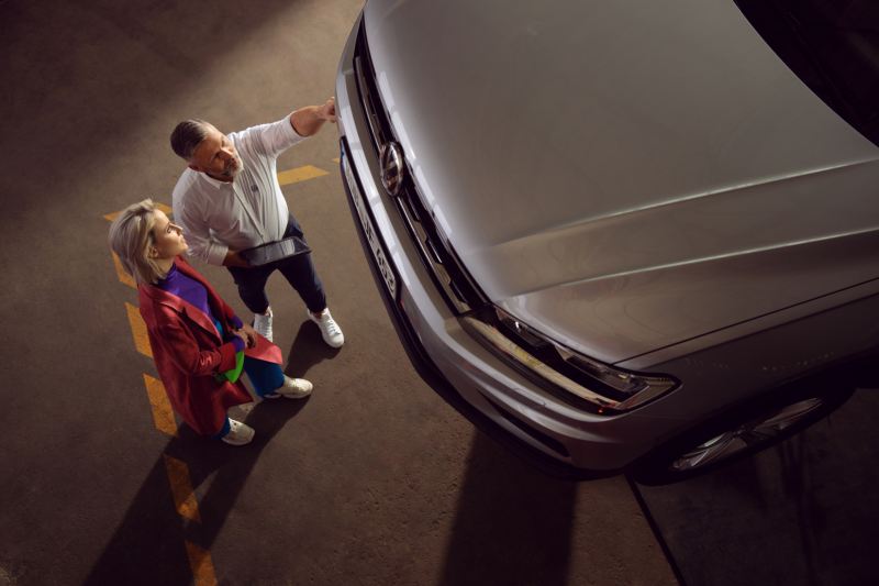 A VW Service Advisor showing a customer the work carried out by their VW Technicain to their Silver Volkswagen under the Volkswagen Service Plan