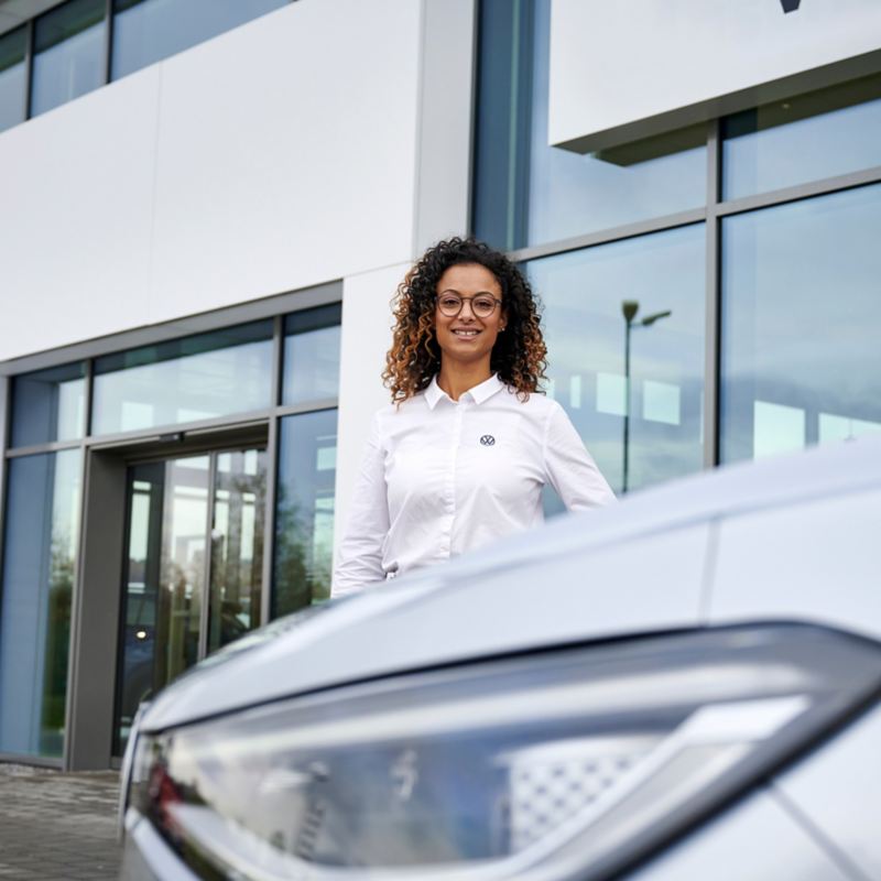 Volkswagen employee at a service center with a white vehicle.