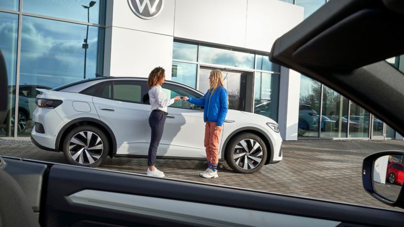 Une cliente remet la clé de son véhicule électrique au collaborateur de l’atelier VW