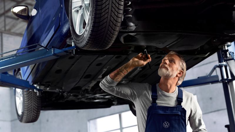 man looking under the car at shock absorbers