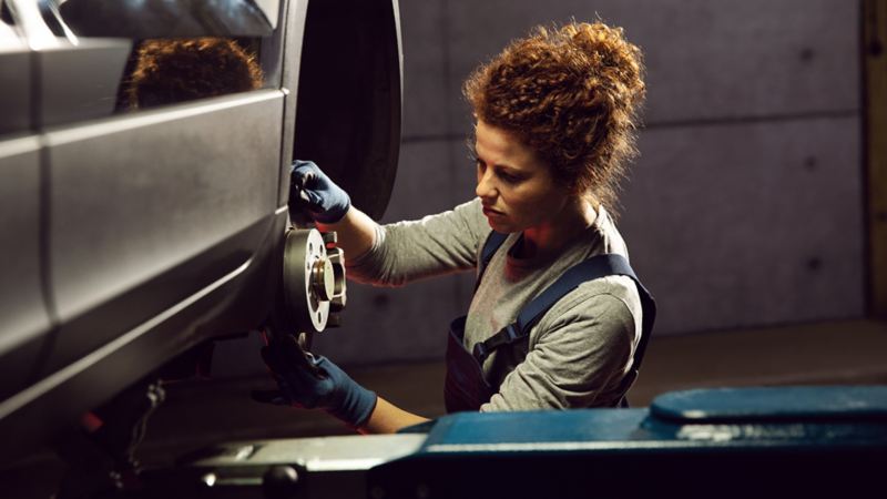 A woman checking tires of a car