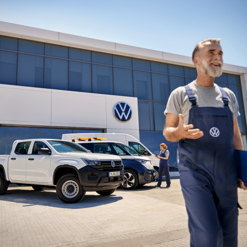 Dos personas del servicio técnico de VW con el VW Amarok, el VW ID. Buzz y el VW Nuevo Crafter aparcados detrás.