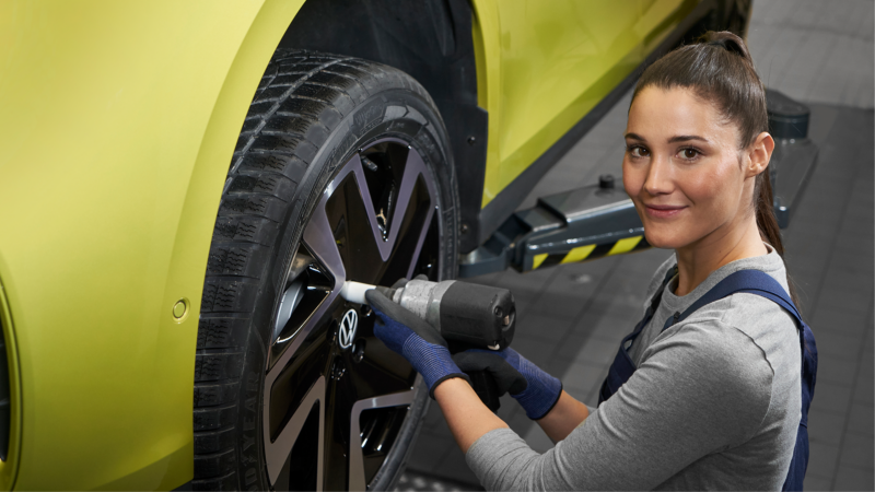 Una mujer del servicio técnico de VW cambiando una rueda.
