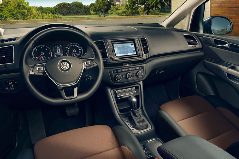Detailansicht des VW Sharan "Black Style" Cockpit mit Multifunktionslenkrad, Chrom-Applikationen und Bi-Color-Ledersitzen.
