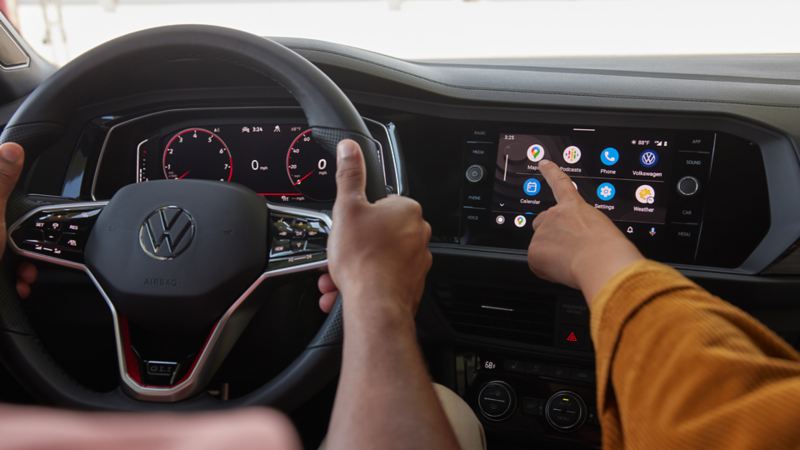 2 people are sitting inside of the 2023 Volkswagen Jetta GLI interacting with the Digital Cockpit Pro
