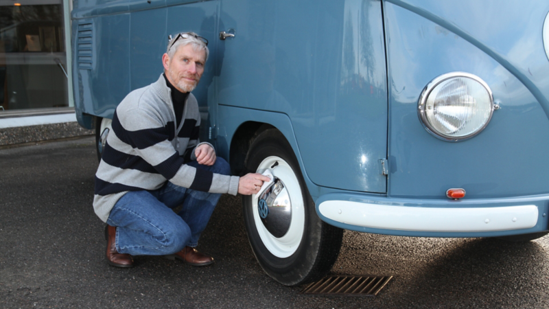 En mand sidder på hug ved fordækket på en transporter fra 1950