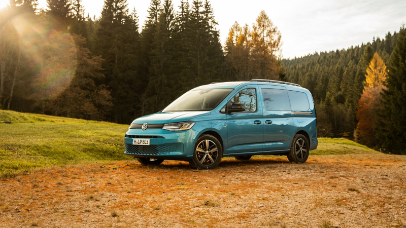 Der VW Caddy California steht auf einer Waldlichtung.
