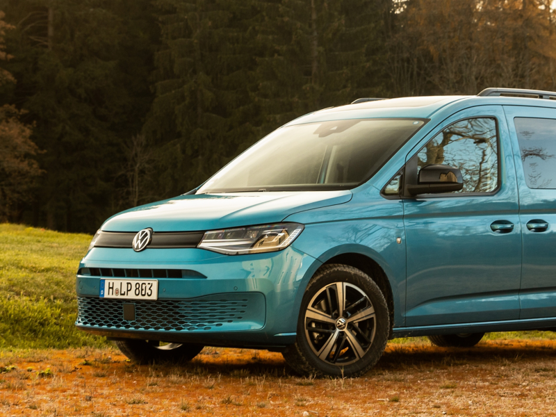 Der VW Caddy California steht auf einer Waldlichtung.